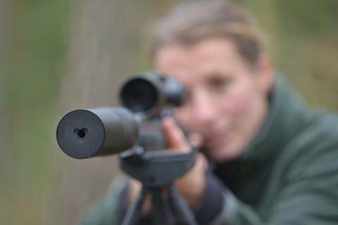 Eine Jägerin schießt mit einer Jagdwaffe mit Schalldämpfer