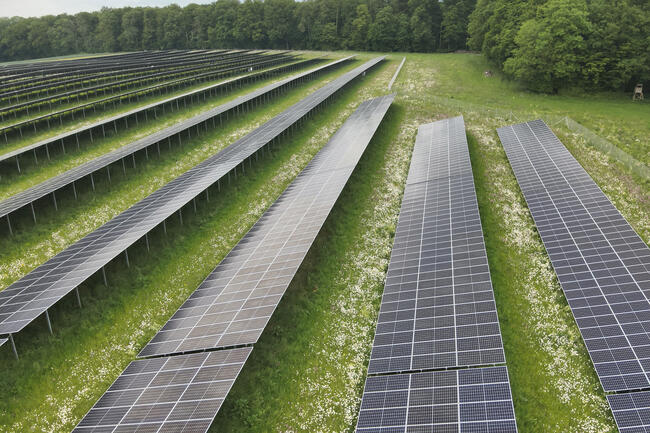 Luftaufnahme einer klassischen Freiflächen-Photovoltaik-Anlage mit Südausrichtung.